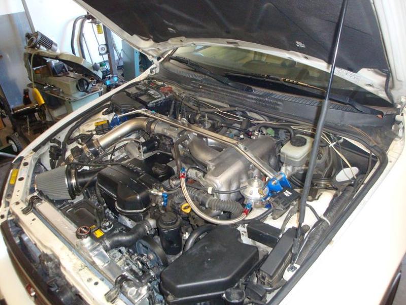 Installed Megan Racing Race-Spec strut tower bar in a Lexus IS300 engine bay, bridging the shock towers for increased rigidity