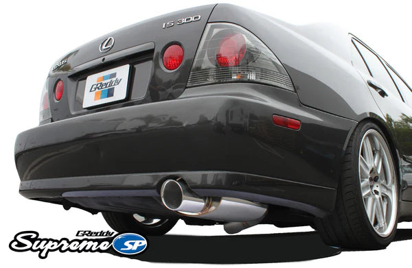 Rear view of a Lexus IS300 featuring the GReddy Supreme SP catback exhaust, showing the signature oval muffler and polished tip